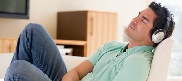 Man on couch with headphones listening